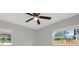 Bedroom featuring a ceiling fan, two windows overlooking a wood fence, and gray walls at 10218 Lola St, Tampa, FL 33612