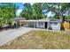 Charming home with a gray painted exterior, large front yard, and covered parking at 10218 Lola St, Tampa, FL 33612