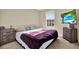 Bright bedroom featuring neutral walls, carpet, and window; dresser and television included at 11443 Cay Spruce Way, San Antonio, FL 33576