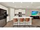 Stylish kitchen featuring white cabinetry, stainless steel appliances, a large island, and sleek bar stools at 11443 Cay Spruce Way, San Antonio, FL 33576