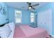 Bright bedroom with a ceiling fan, pink bedspread, and light blue walls at 1240 Georgia Ave, Dunedin, FL 34698