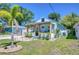 Inviting blue cottage featuring a covered porch, lush lawn, and mature palm tree at 1240 Georgia Ave, Dunedin, FL 34698