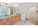 Bathroom featuring double sink vanity, granite counters, travertine floors, and a glass block window at 12801 Castlemaine Dr, Tampa, FL 33626