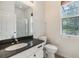 Bathroom with a granite countertop, white cabinets, a walk-in shower, and window allowing natural light at 12801 Castlemaine Dr, Tampa, FL 33626