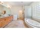 Bright bathroom featuring double vanity, a garden tub and a walk-in shower with unique glass block accents at 12801 Castlemaine Dr, Tampa, FL 33626