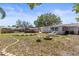 A shot of the expansive backyard with a fire pit, seating, and a large shade tree at 1344 Dartmouth Dr, Holiday, FL 34691