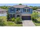 Charming two-story home with blue siding, stone accents, a dark garage door and landscaped yard at 13871 Carlow Park Dr, Riverview, FL 33579