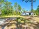 Backyard featuring mature trees and green grass surrounding the back of a light blue home at 14020 Sooty Tern Ave, Brooksville, FL 34614