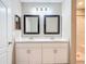 Bathroom featuring double sinks, white cabinets, framed mirrors, and a shower at 14020 Sooty Tern Ave, Brooksville, FL 34614
