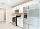 Well-lit kitchen featuring stainless steel appliances, white cabinets, and tile flooring at 14020 Sooty Tern Ave, Brooksville, FL 34614
