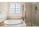 Bathroom featuring a large tub, glass-enclosed shower, and bright window at 14418 Mirabelle Vista Cir, Tampa, FL 33626