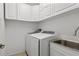 Laundry room with modern washer and dryer, stainless steel sink, and white cabinets at 14418 Mirabelle Vista Cir, Tampa, FL 33626