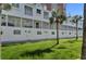 Exterior showcasing a building with balconies, updated windows, and a lawn with palm trees at 17960 Gulf Blvd # 111, Redington Shores, FL 33708