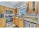 Well-lit kitchen features stainless steel appliances, granite countertops, and natural wood cabinetry at 17960 Gulf Blvd # 111, Redington Shores, FL 33708