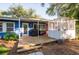A blue house has a wooden deck and sunroom outside surrounded by a natural landscape at 1880 Belleair Rd, Clearwater, FL 33764