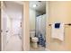 Bathroom featuring a toilet and shower with a white and blue curtain, with a towel rack on the right at 1880 Belleair Rd, Clearwater, FL 33764