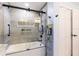 Modern bathroom featuring a tub with sliding glass doors, gray tile, and built in toiletry storage at 1880 Belleair Rd, Clearwater, FL 33764