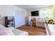 Bedroom with wood floors, closet, TV and white desk under the window with light yellow curtains at 1880 Belleair Rd, Clearwater, FL 33764