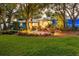 Charming blue home featuring a cozy patio with seating, surrounded by lush greenery and mature trees at 1880 Belleair Rd, Clearwater, FL 33764