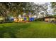 Expansive green lawn view featuring a charming home and inviting outdoor seating area amid mature trees at 1880 Belleair Rd, Clearwater, FL 33764