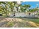 Home exterior featuring porch and sidewalk access, with landscaping, trees, and a clear blue sky at 27477 Old Trilby Rd, Brooksville, FL 34602