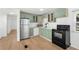 Well-lit kitchen featuring stainless steel refrigerator, white countertops, and green cabinets at 27477 Old Trilby Rd, Brooksville, FL 34602