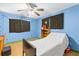View of small bedroom featuring a ceiling fan, wood-look floors, and blue walls at 29133 Lawton Dr, Nobleton, FL 34661