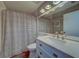 Well-lit bathroom with marble vanity, single sink, and shower with striped curtain at 3135 Charter Club Dr # G, Tarpon Springs, FL 34688