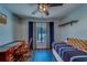 Bedroom featuring desk, dark-toned floors, ceiling fan, large window with curtains, and floating shelves at 3135 Charter Club Dr # G, Tarpon Springs, FL 34688