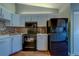 Modern kitchen featuring white cabinets, black appliances, mosaic backsplash, and vinyl floors at 3135 Charter Club Dr # G, Tarpon Springs, FL 34688