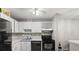 Galley kitchen featuring white cabinetry and black appliances at 3241 Fox Chase N Cir # 106, Palm Harbor, FL 34683
