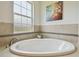 Large soaking bathtub with a tiled surround and bright window at 32791 Natural Bridge Rd, Wesley Chapel, FL 33543