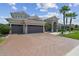 Inviting home featuring a three-car garage, large brick driveway, and manicured lawn at 32791 Natural Bridge Rd, Wesley Chapel, FL 33543