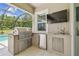Outdoor kitchen with stainless grill, fridge, sink, tv, and outdoor access at 32791 Natural Bridge Rd, Wesley Chapel, FL 33543