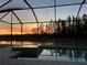 Swimming pool, spa, and tranquil water view during sunset on a screened-in lanai at 32791 Natural Bridge Rd, Wesley Chapel, FL 33543