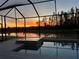 Screened-in pool with a connected spa offering relaxing sunset views over the pond and greenery at 32791 Natural Bridge Rd, Wesley Chapel, FL 33543