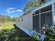 Exterior view of home's vinyl siding, screened-in porch, complemented by the surrounding lawn and greenery at 34141 Tree Lake Dr, Wesley Chapel, FL 33543