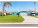 A charming teal house features a well-manicured lawn, garage and a boat parked to the side at 525 Lillian Dr, Madeira Beach, FL 33708