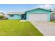 Charming teal home featuring an attached garage, beautiful lawn, and inviting curb appeal at 525 Lillian Dr, Madeira Beach, FL 33708