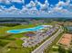 An aerial view features a blue lagoon, green spaces, road, and planned neighborhood, and surrounding landscape at 5329 Windy Grove Dr, Wimauma, FL 33598