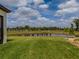 Lush backyard with vibrant green grass and a serene pond view, enhanced by meticulous landscaping and an iron fence at 5329 Windy Grove Dr, Wimauma, FL 33598
