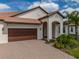 Charming single-story home featuring a tile roof, two-car garage, and inviting front yard with lush landscaping at 5329 Windy Grove Dr, Wimauma, FL 33598
