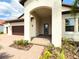 Inviting front porch with brick pavers and an arched entryway leading to the stylish blue front door at 5329 Windy Grove Dr, Wimauma, FL 33598