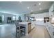 Well-lit kitchen featuring white cabinets, stainless steel appliances, a large island, and an adjacent dining area at 5329 Windy Grove Dr, Wimauma, FL 33598