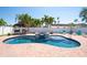 Wide view of the kidney-shaped pool and spa with stone accents, brick patio and lush palms at 5921 Denver Ne St, St Petersburg, FL 33703