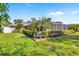Lush backyard featuring a screened pool enclosure, framed by manicured hedges and vibrant green grass, offering a private oasis at 6790 Burning Tree Dr, Seminole, FL 33777
