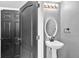 Bathroom with a pedestal sink, oval mirror, and stylish lighting, adjacent to a gray paneled door at 6851 Breezy Palm Dr, Riverview, FL 33578