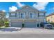 Two-story townhome featuring gray exterior, a pair of balconies, three garage doors, and well-maintained landscaping at 6851 Breezy Palm Dr, Riverview, FL 33578