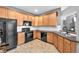 A bright kitchen features wood cabinets, black appliances, and tile flooring for a warm and inviting space at 6851 Breezy Palm Dr, Riverview, FL 33578