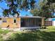 A yellow home with a screened in back porch, plants, and a well maintained green grass in the backyard at 844 67Th S St, South Pasadena, FL 33707